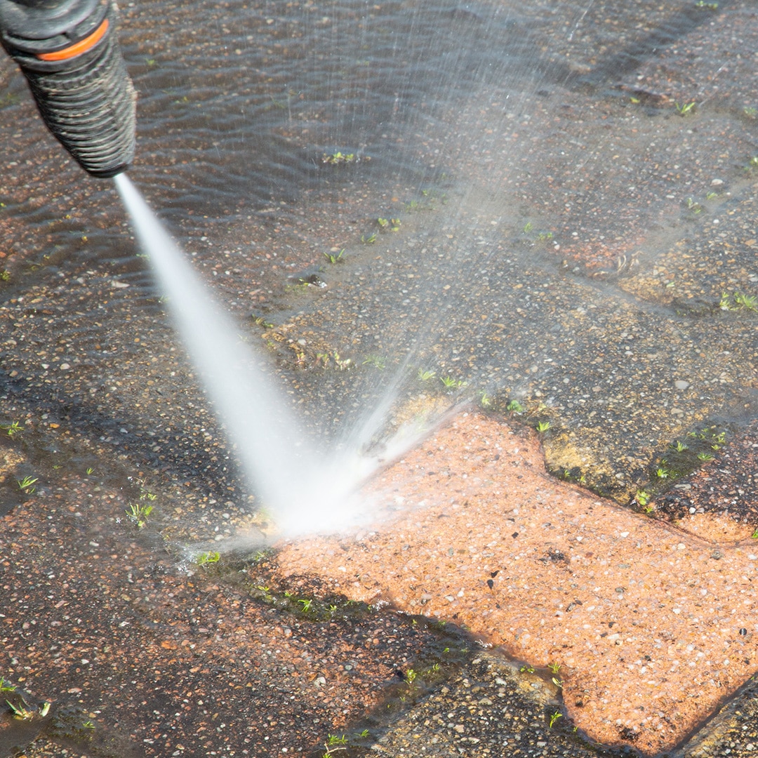 Pressure washer removing moss from brick surface
