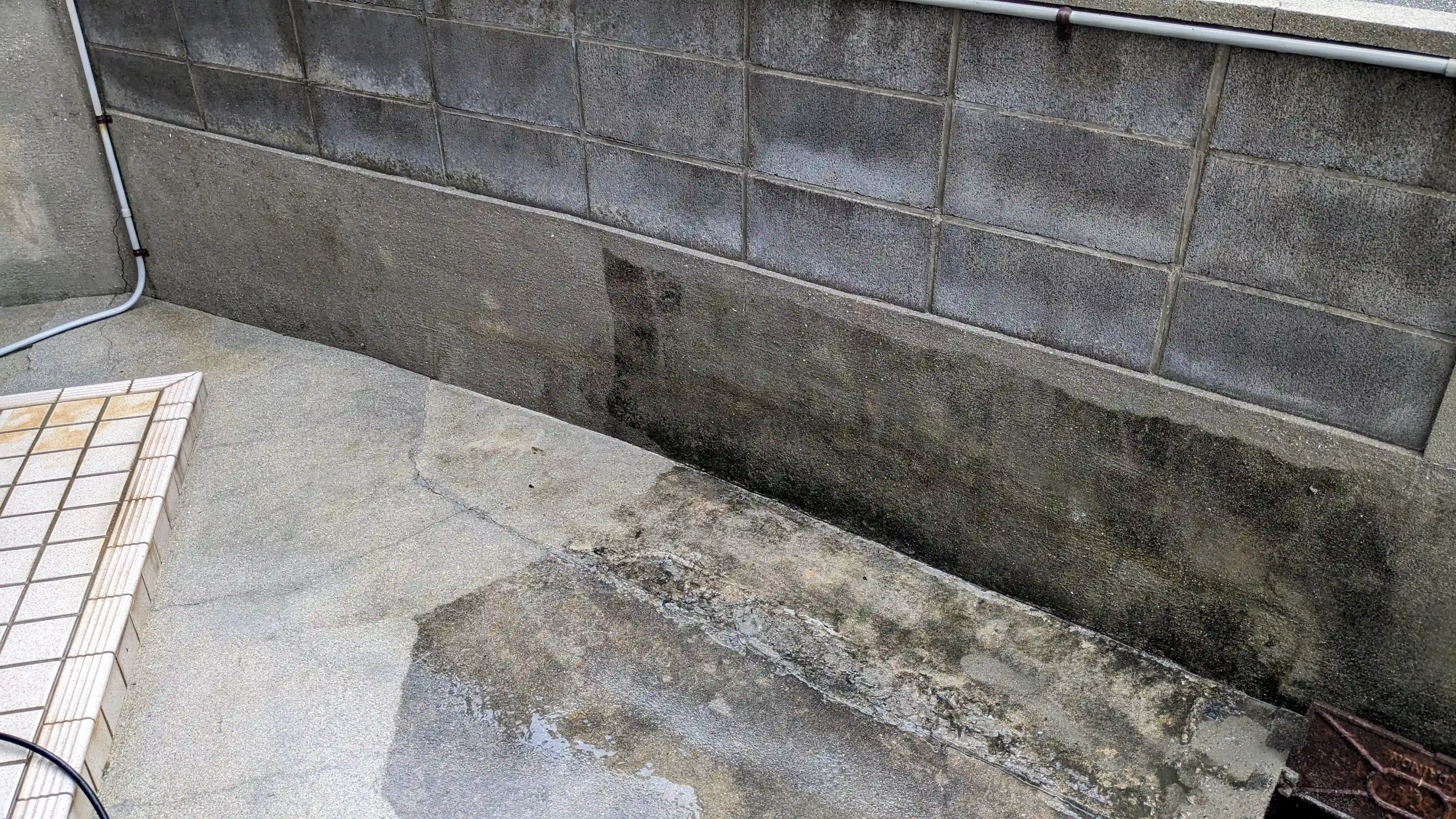 Concrete wall base and walkway mid cleaning beside a Japanese house